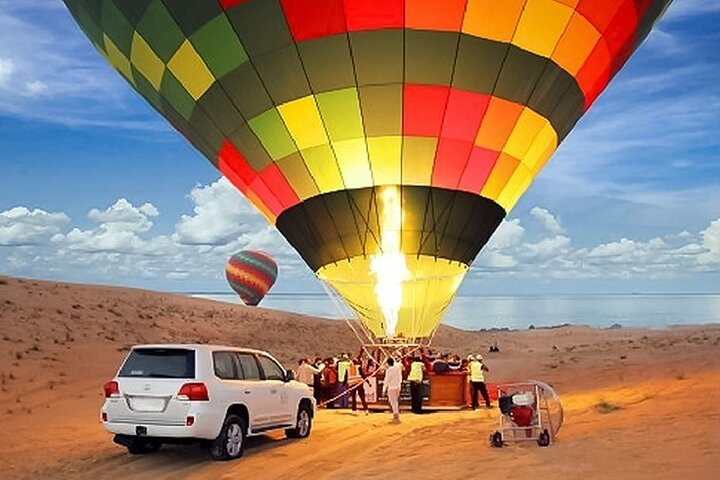 Soar high above the Dubai Desert in a colorful hot air balloon witnessing breathtaking views while preparing for an unforgettable adventure filled with breakfast camel rides and quad biking.